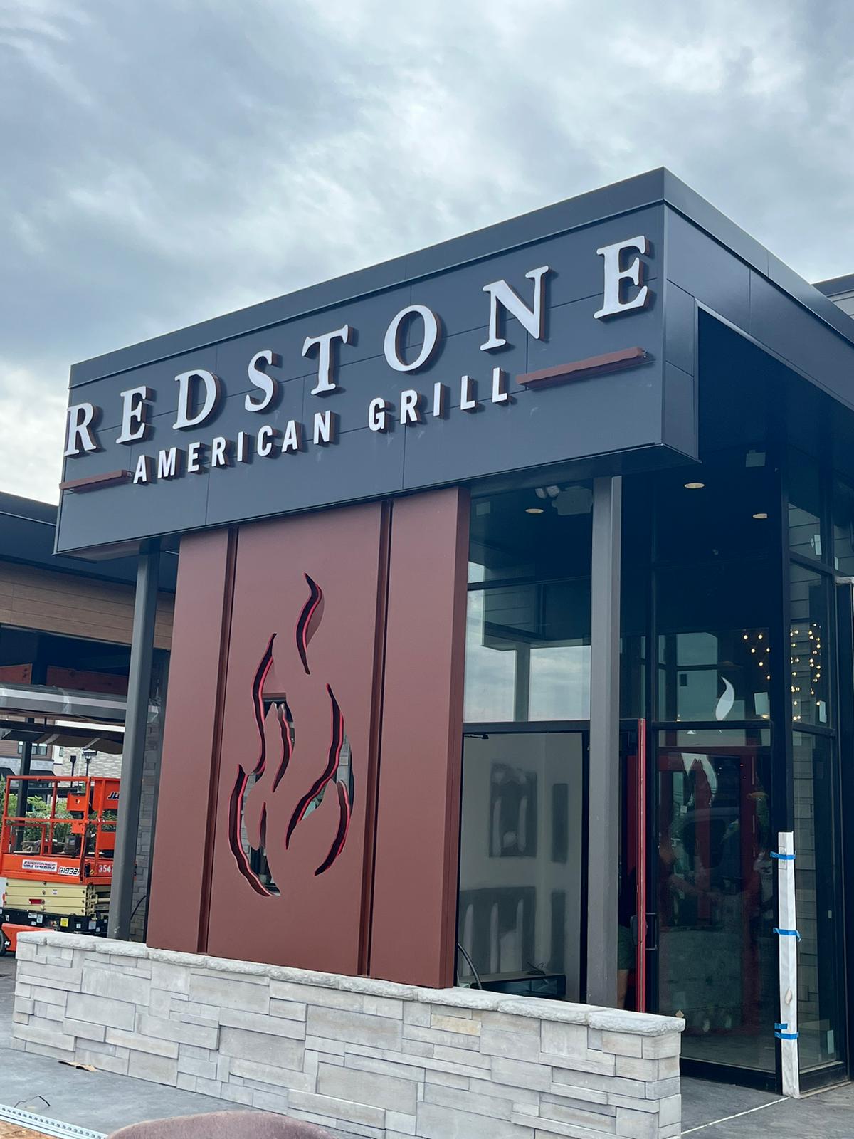 Illuminated channel-letter sign and dimensional flame logo at Redstone American Grill entrance