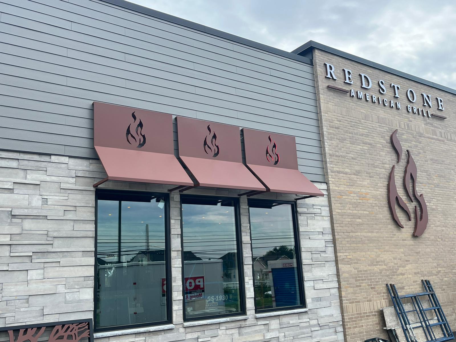 Redstone American Grill exterior sign program — wordmark, dimensional flame logos, and branded canopies